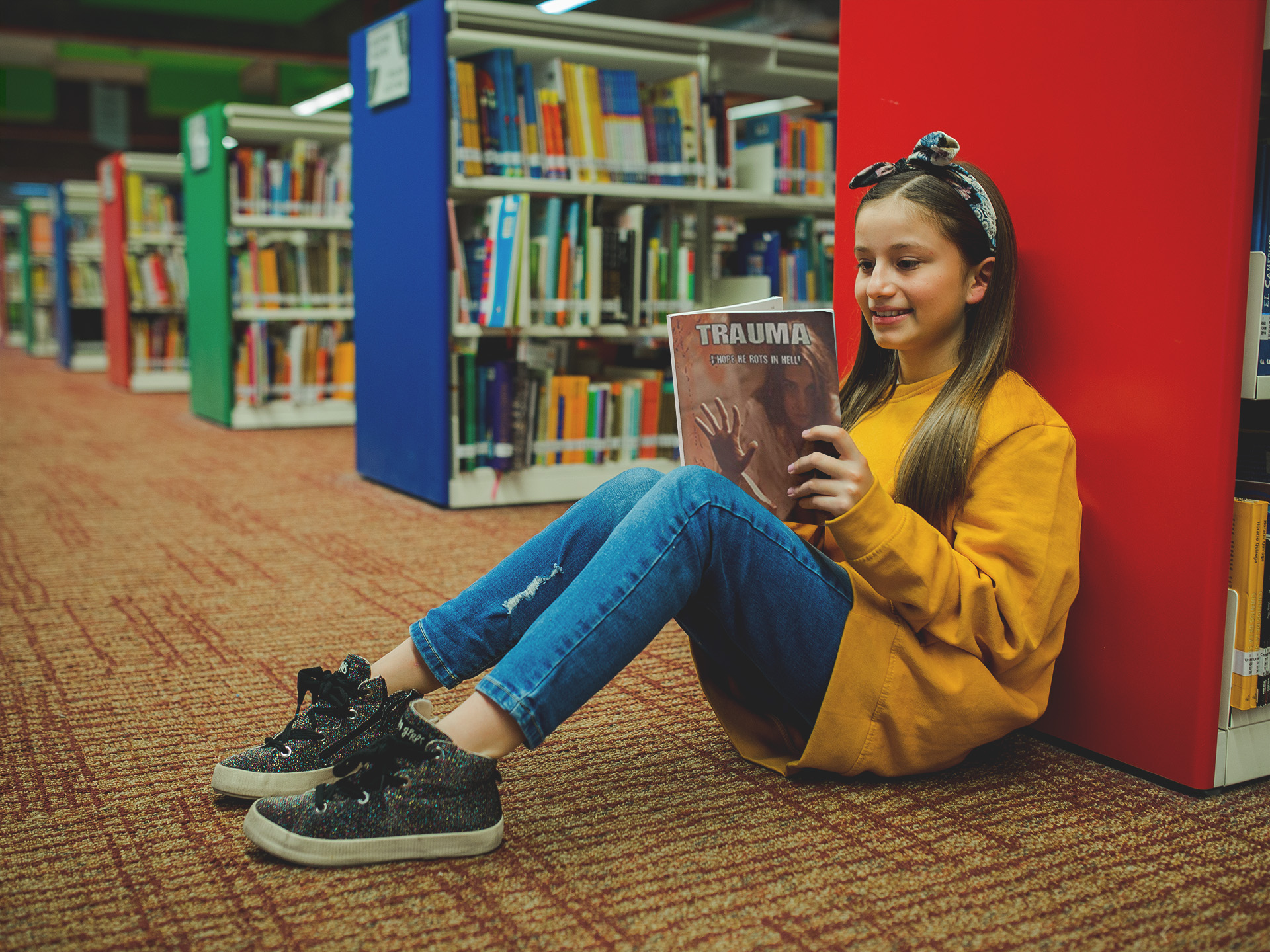girl-with-a-yellow-sweater-reading-trauma-sitting-at-the-library
